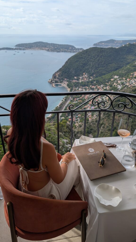 Aude installée à table sur le balcon de Château Eza, face à la mer