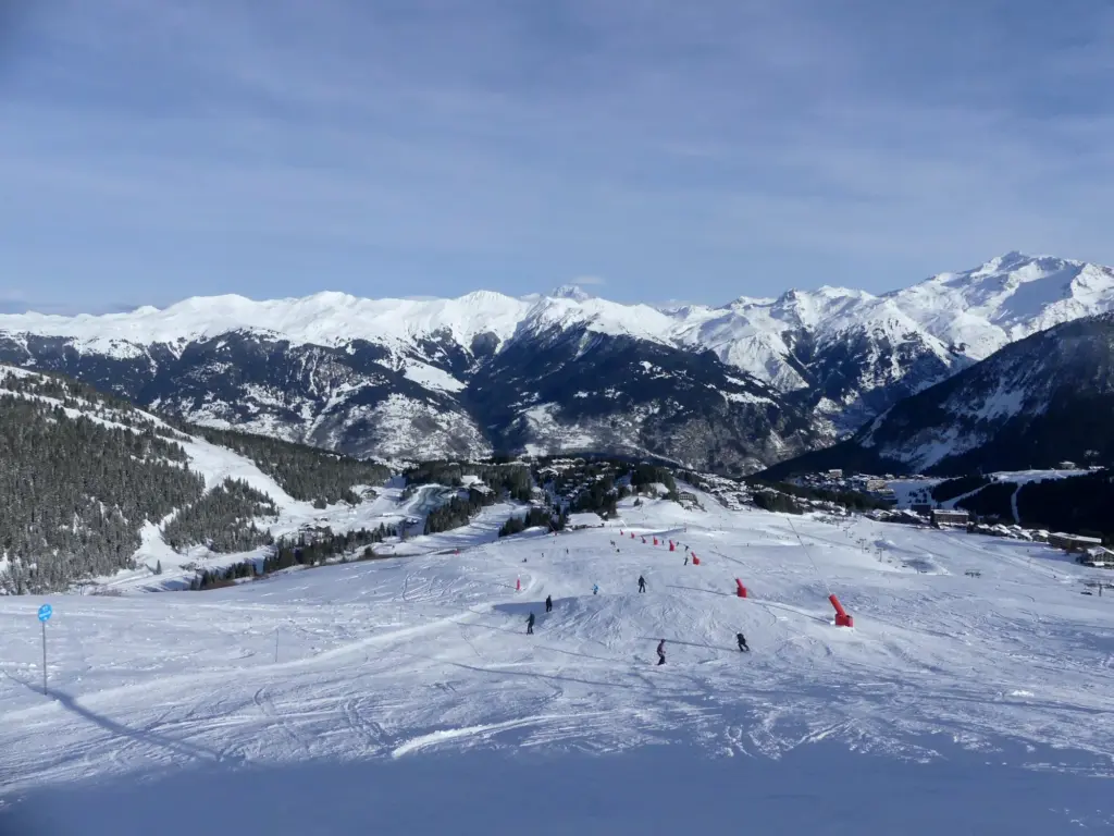 Piste enneigée descendant vers Courchevel 1850, avec les montagnes en arrière-plan