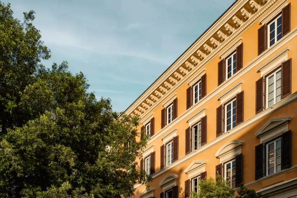 Façade ocre d’Experimental Roma sur la Via Ludovisi, avec ses volets sombres et les arbres voisins