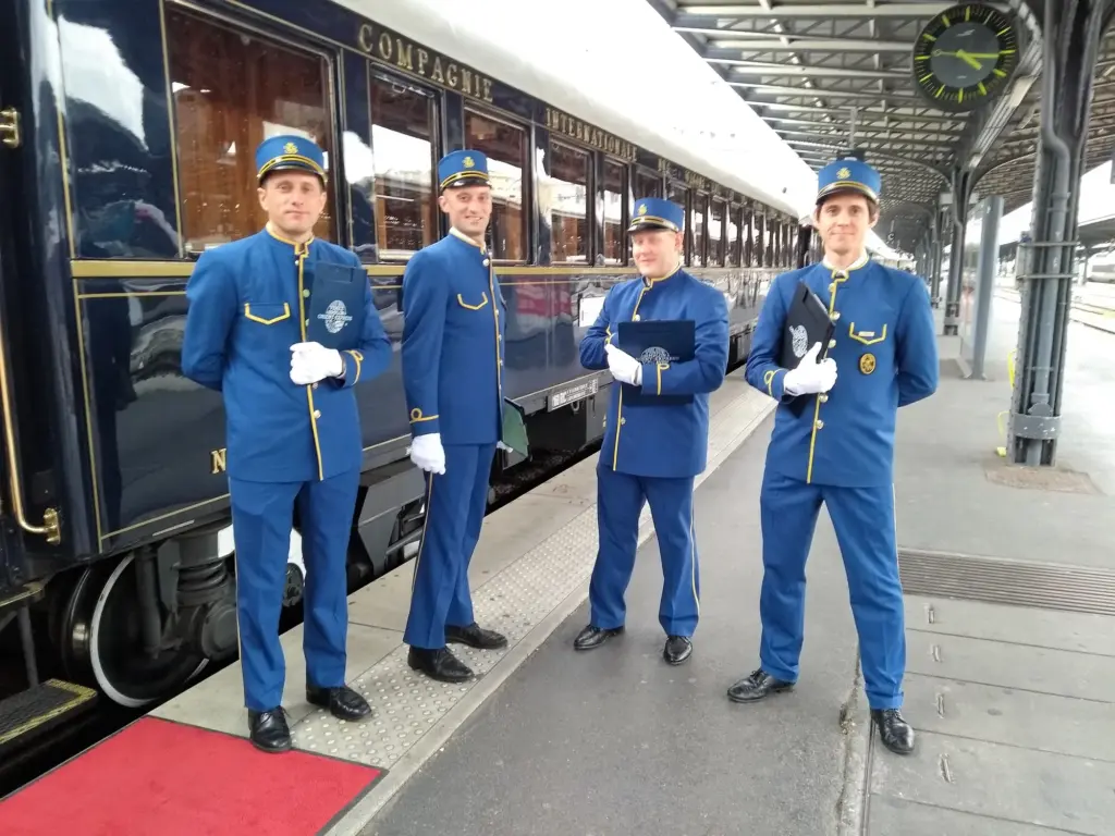 Personnel en uniforme devant une voiture du Venice Simplon-Orient-Express