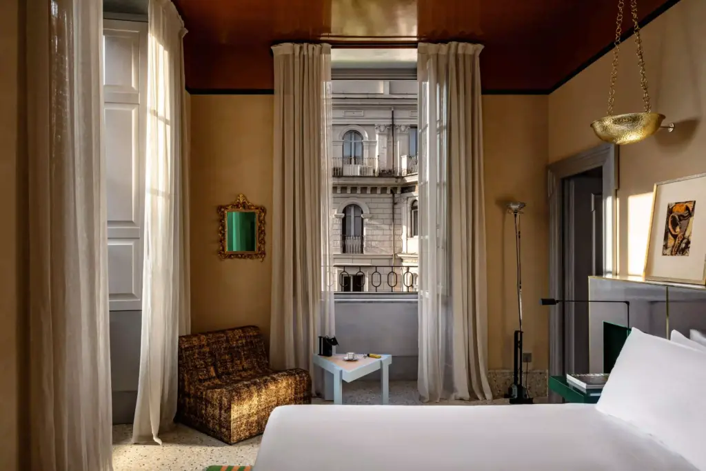 Chambre d’Experimental Roma avec de hauts rideaux clairs, un plafond coloré et une fenêtre sur la ville