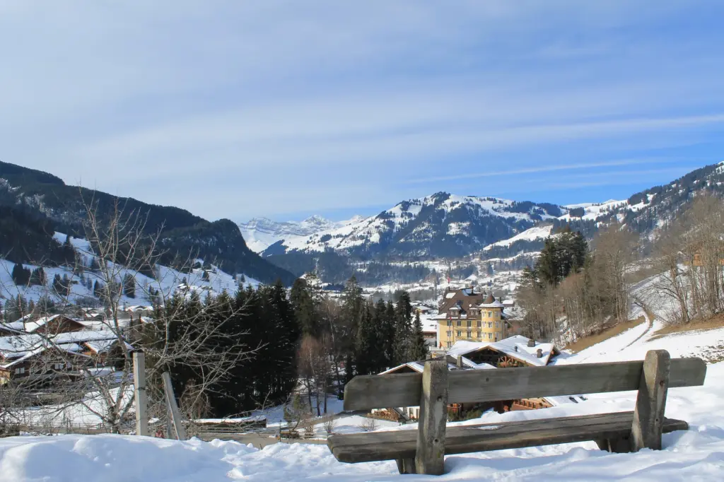 Banc enneigé au-dessus de Gstaad, avec des chalets et les montagnes du Saanenland