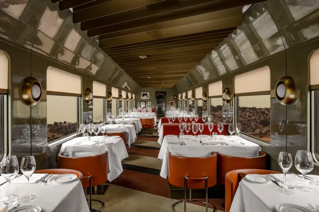 Tables dressées et fauteuils orange dans le restaurant de La Dolce Vita Orient Express