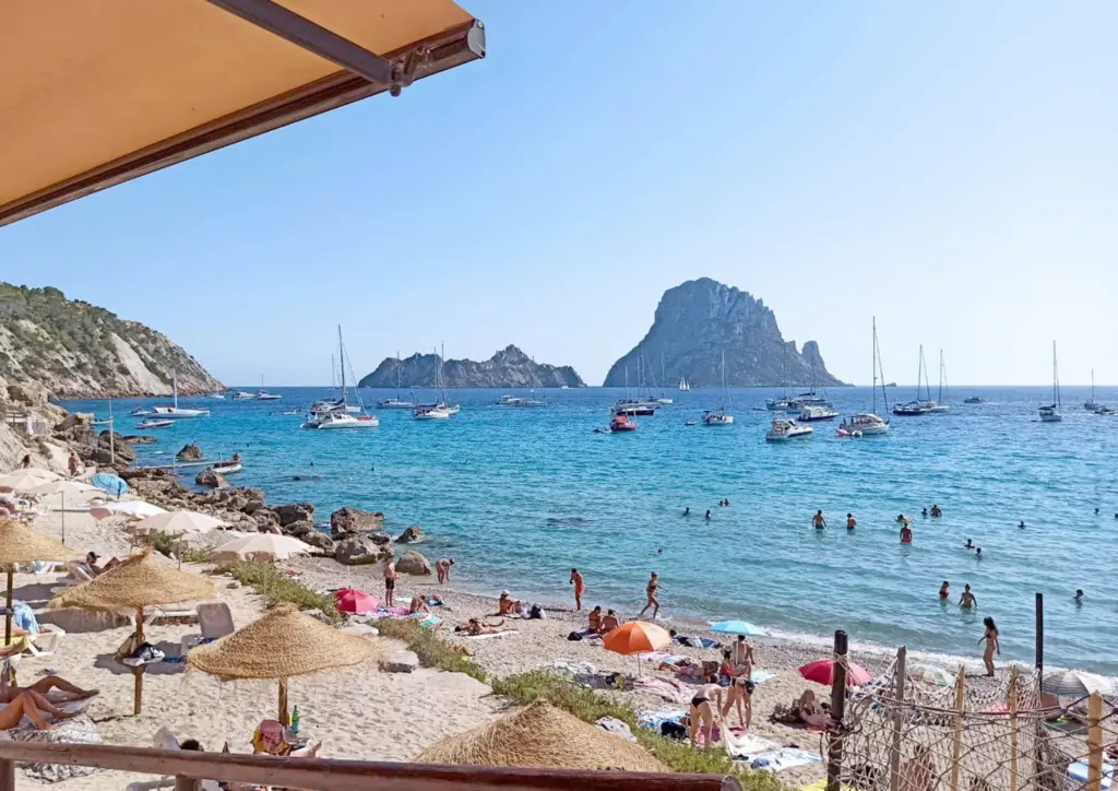 La plage de Cala d’Hort avec les bateaux au mouillage et Es Vedrà à l’horizon