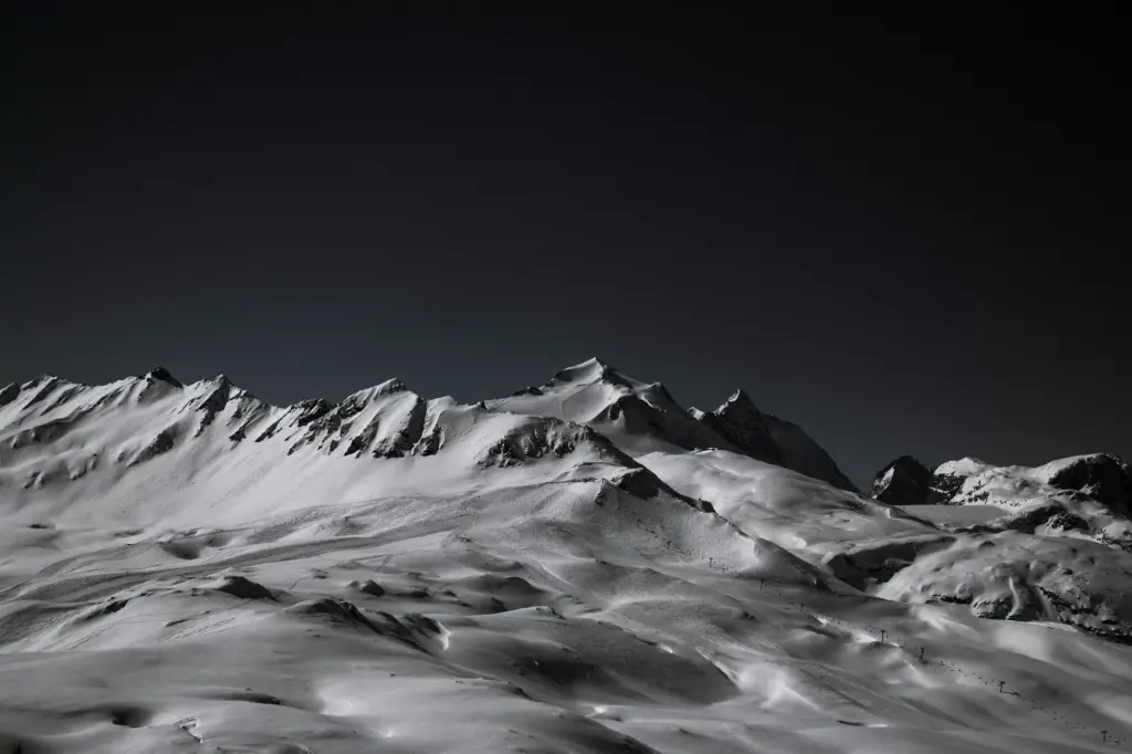 Reliefs enneigés de Val d’Isère photographiés de nuit, sous un ciel sombre