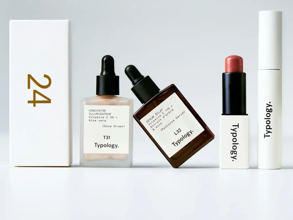 Case 24 du calendrier de l’Avent Typology 2026 à côté du concentré illuminateur, du sérum éclat, d’un rouge à lèvres et d’un mascara de la marque