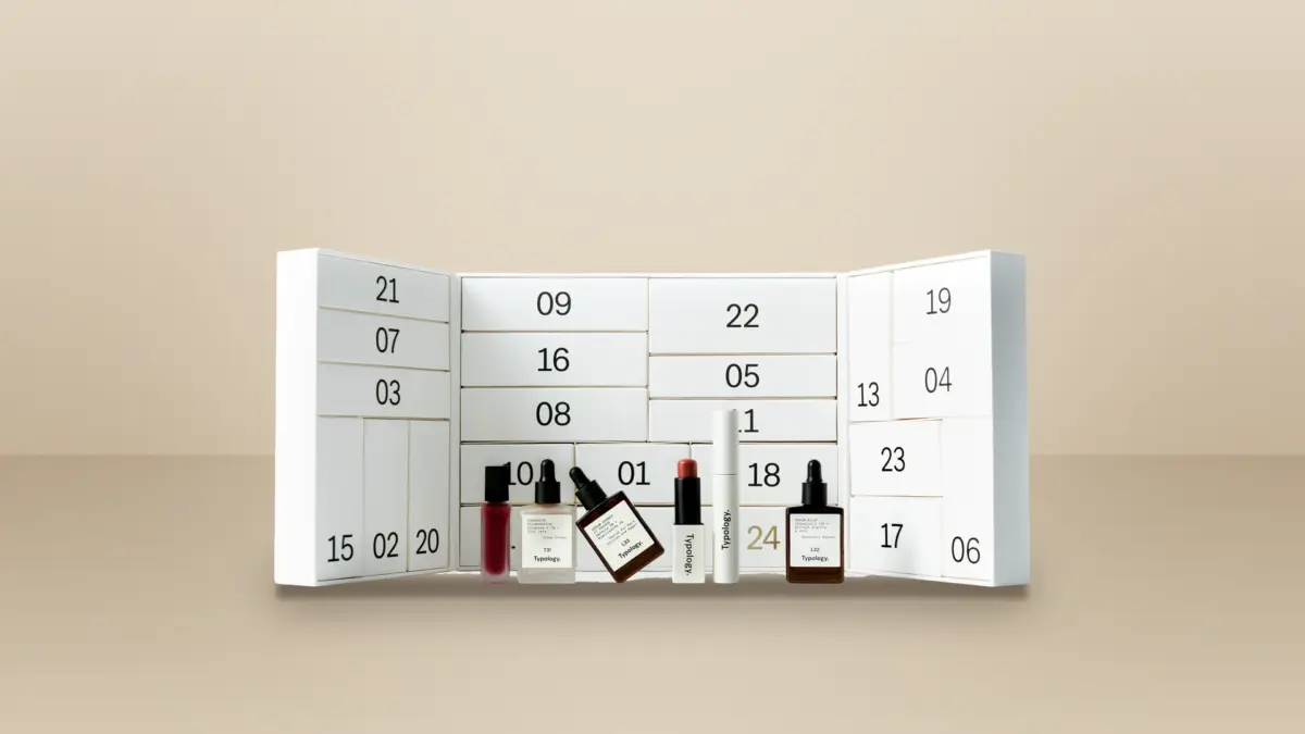 Calendrier de l’Avent Typology 2026 ouvert, ses 24 cases blanches et cinq soins de la marque posés devant, sur fond beige