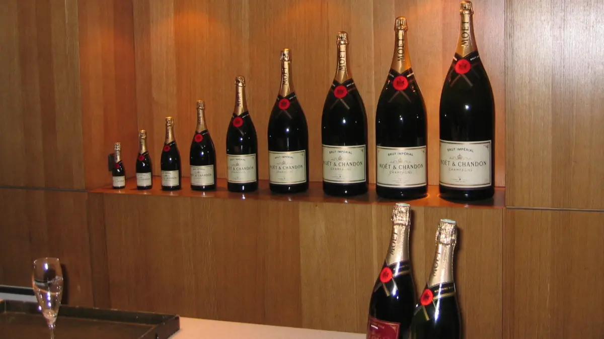 Bouteilles Moët & Chandon de formats variés alignées sur une étagère en bois