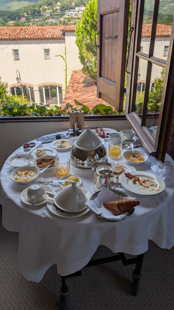 Petit-déjeuner en chambre près de la fenêtre ouverte sur les toits et les jardins