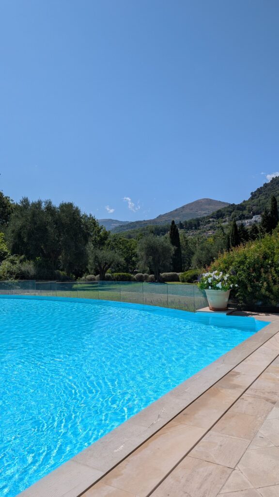Piscine turquoise du château entourée de végétation et de collines