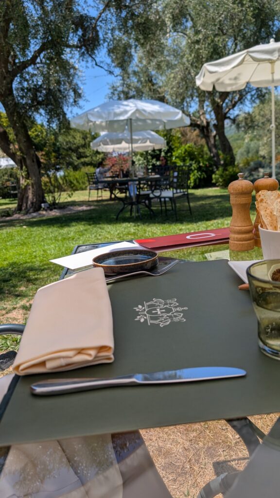 Tables de L’Oliveraie dans le jardin sous les arbres et les parasols
