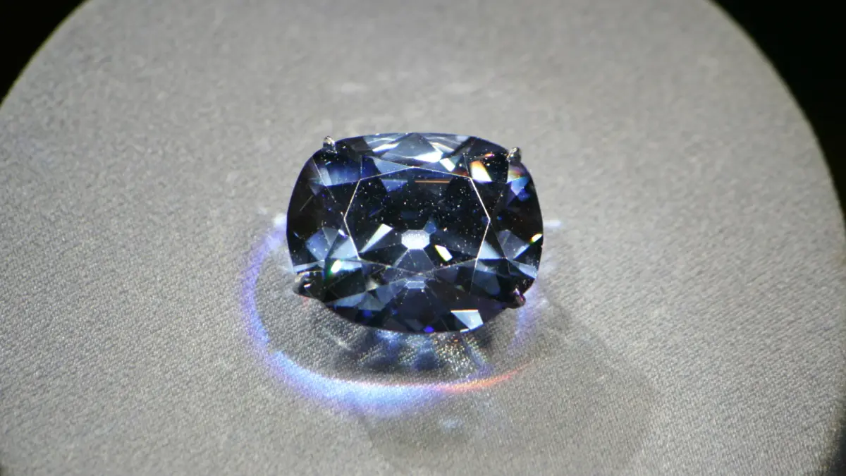 Le diamant CTF Pink Star facetté posé sur un coussin gris, avec reflets bleutés
