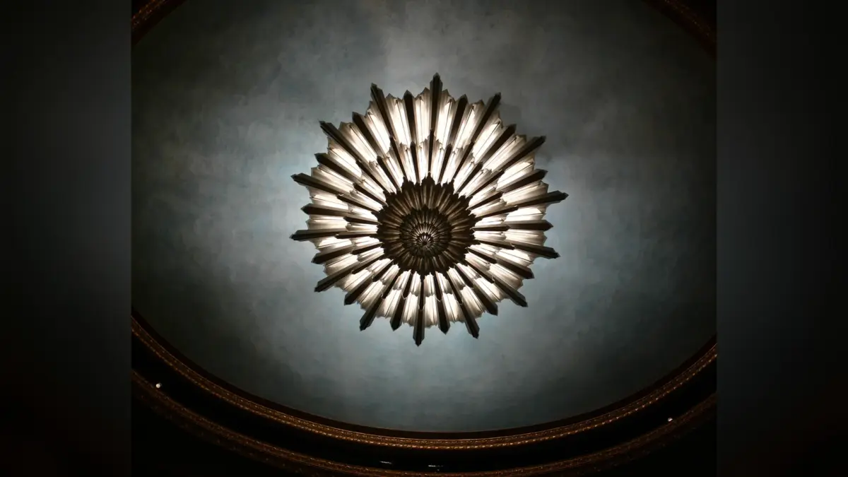 Lustre Art déco circulaire à pampilles lumineuses fixé au centre d’un plafond sombre