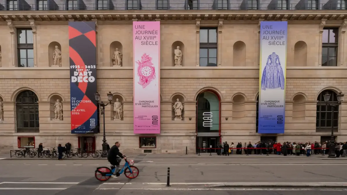Façade du Musée des Arts décoratifs à Paris ornée de bannières, avec cycliste et file de visiteurs