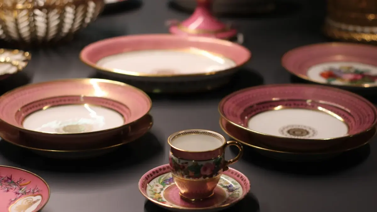 Service en porcelaine à bord rose et doré avec tasse et assiettes sur table sombre