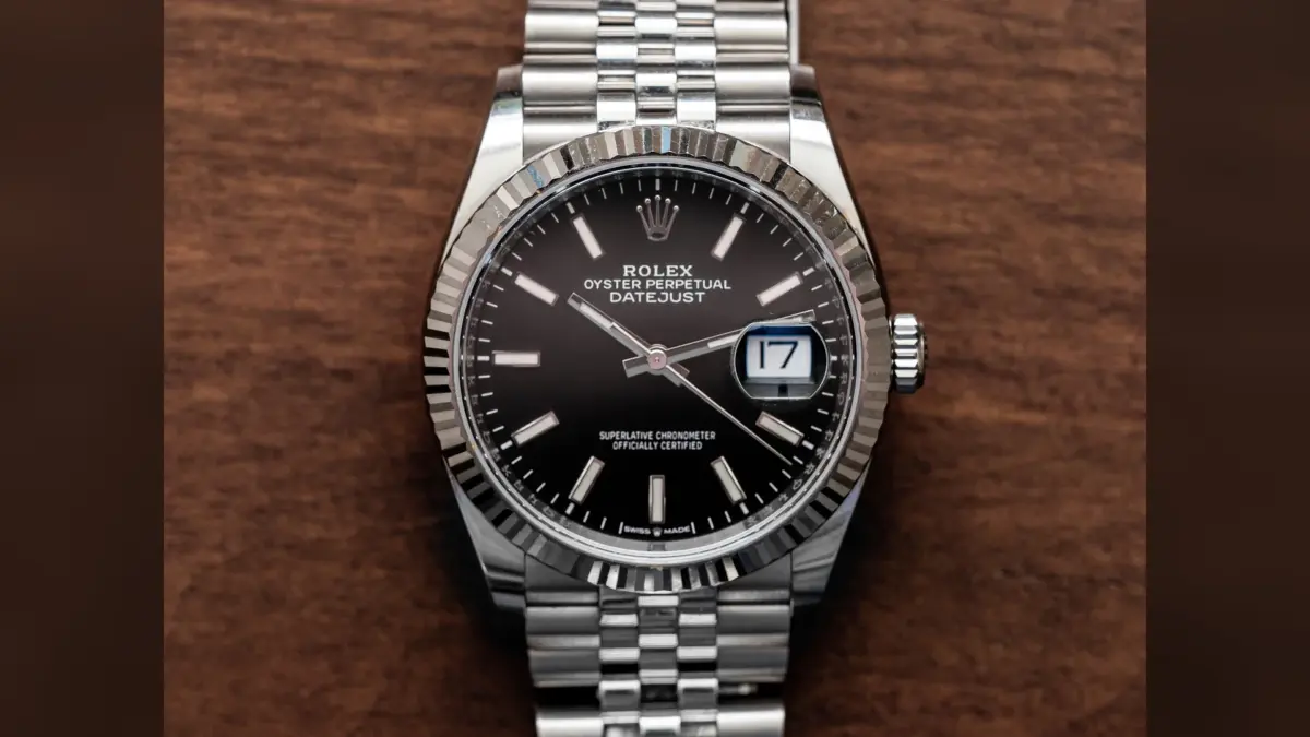 Rolex Datejust en acier avec cadran noir, lunette cannelée et bracelet Jubilee sur bois